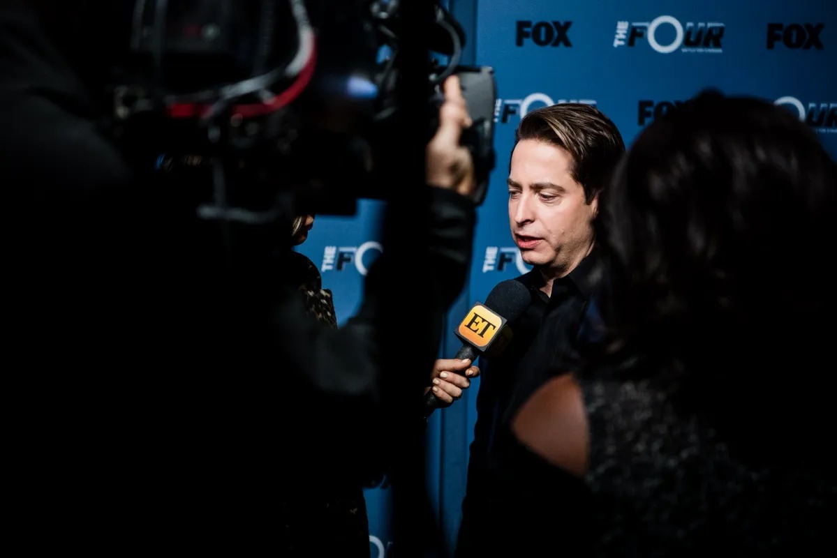 Man being interviewed by camera crews at a dark press line