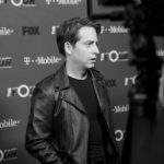 Man posing in front of a sponsor press backdrop