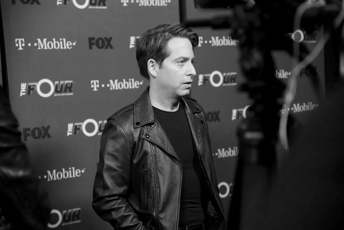 Man posing in front of a sponsor press backdrop