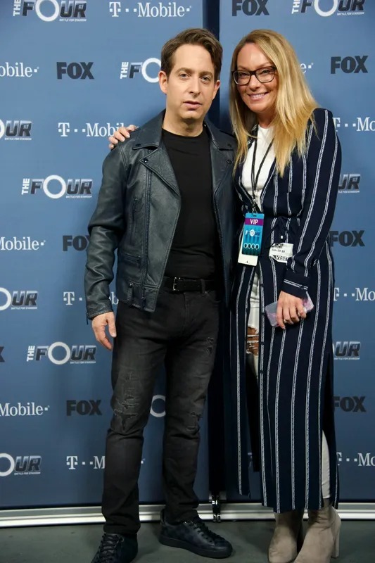 Man and woman posing on a blue press wall