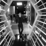 Man walking through a white hexagon-lit tunnel