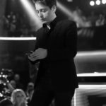 Black and white photo of a man on stage under spotlights
